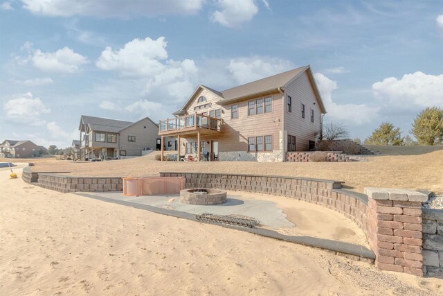 W5611 32nd St, New Lisbon, WI 53950 - rear view of house with a fire pit, stone siding, a deck, and a patio