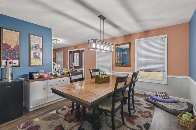 dining area featuring a wainscoted wall, dark wood-style flooring, and visible vents