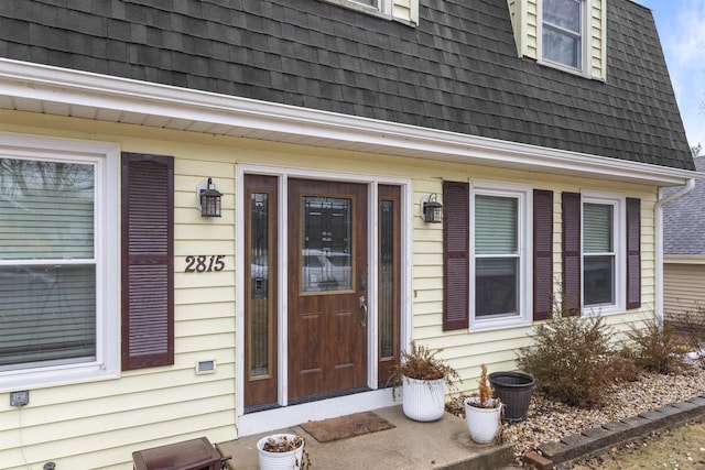 doorway to property featuring a shingled roof and mansard roof