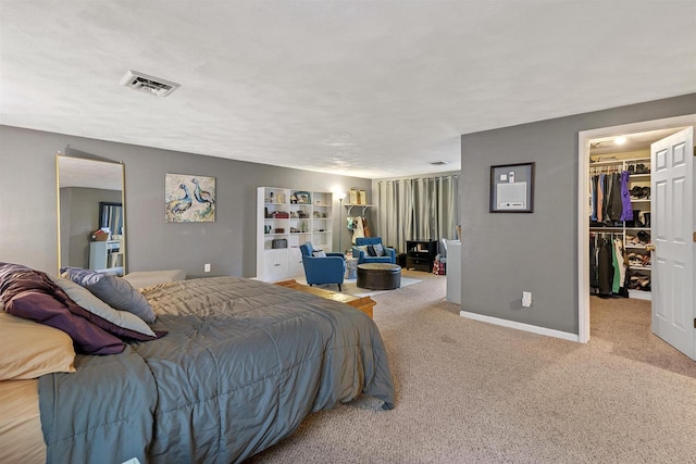 carpeted bedroom featuring a walk in closet, a closet, visible vents, and baseboards