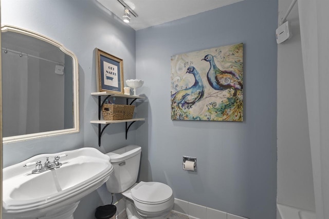 bathroom with track lighting, baseboards, a sink, and toilet