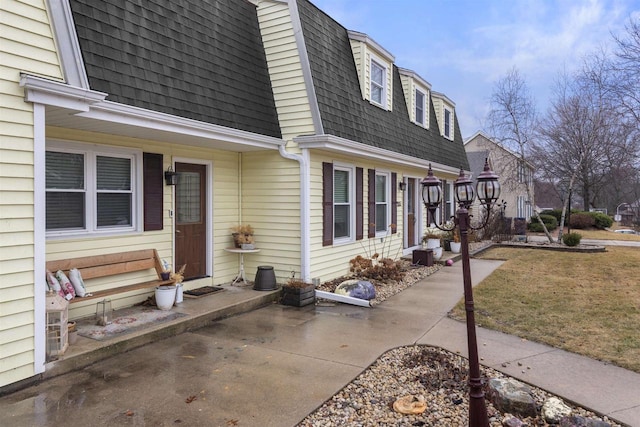 view of home's exterior with a yard and a shingled roof