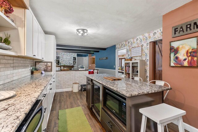 kitchen featuring black microwave, beverage cooler, a breakfast bar area, dark wood-style flooring, and white cabinetry
