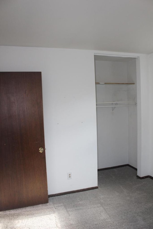 unfurnished bedroom featuring carpet floors, a closet, and baseboards