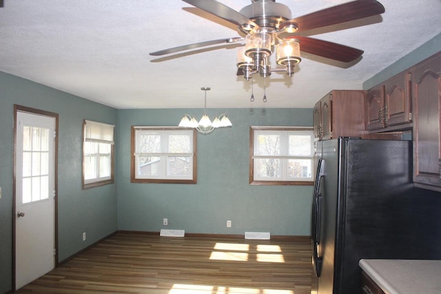 kitchen with light countertops, freestanding refrigerator, a healthy amount of sunlight, and wood finished floors