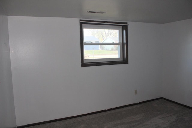 empty room with dark colored carpet, visible vents, and baseboards