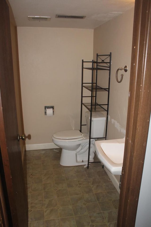 half bath with visible vents, toilet, and baseboards