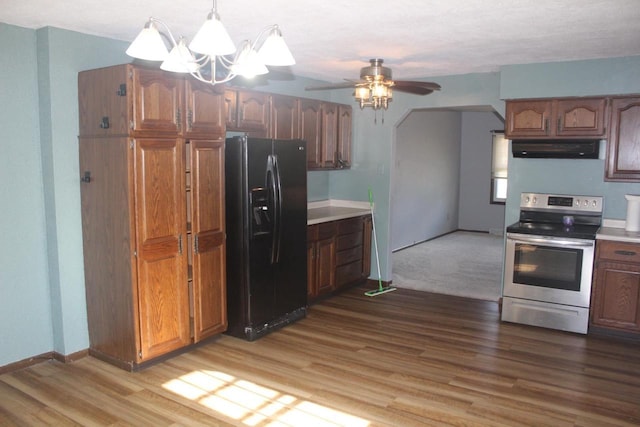 kitchen with under cabinet range hood, wood finished floors, black fridge with ice dispenser, light countertops, and stainless steel electric stove