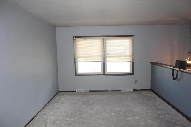 empty room featuring light colored carpet, visible vents, and baseboards