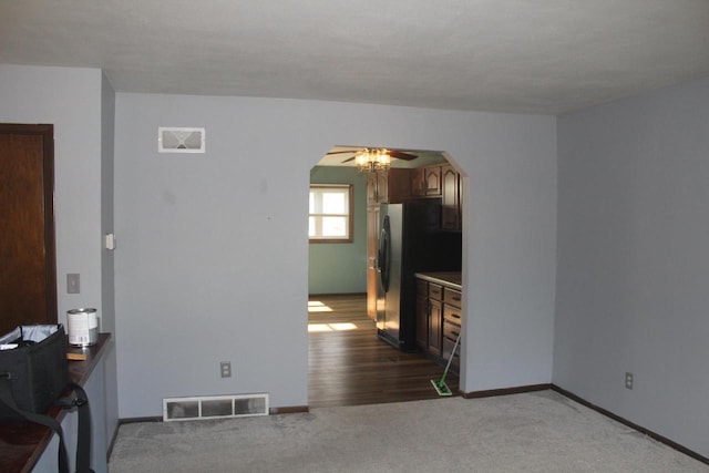 spare room featuring carpet floors, baseboards, visible vents, and arched walkways