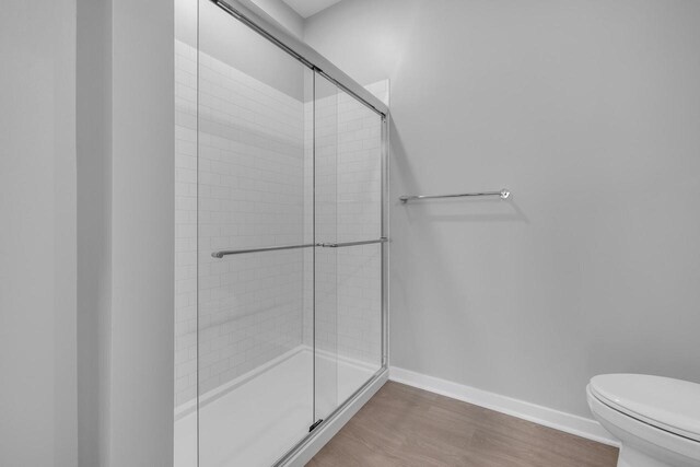500 E Main St Unit 203, Waterford, WI 53185 - bathroom with toilet, baseboards, tiled shower, and wood finished floors