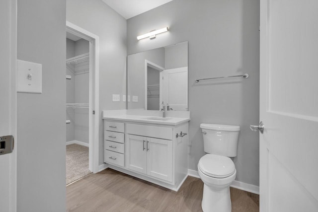 500 E Main St Unit 203, Waterford, WI 53185 - bathroom featuring a walk in closet, toilet, vanity, wood finished floors, and baseboards