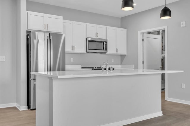 500 E Main St Unit 203, Waterford, WI 53185 - kitchen featuring light wood-style flooring, a kitchen island with sink, appliances with stainless steel finishes, and white cabinets