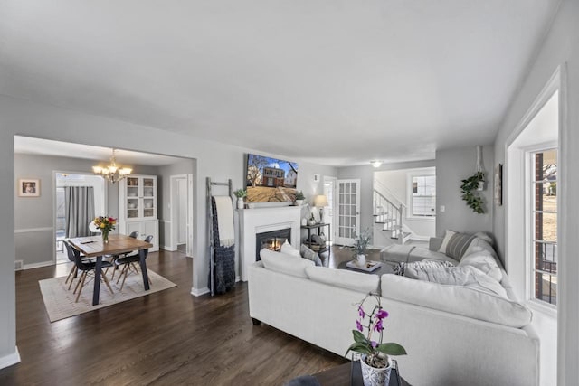 living area with a wealth of natural light, a glass covered fireplace, and dark wood-style flooring