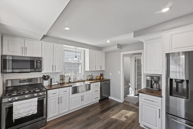 kitchen with a sink, dark wood-style floors, white cabinetry, stainless steel appliances, and decorative backsplash