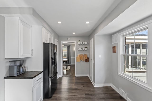 kitchen with visible vents, stainless steel refrigerator with ice dispenser, dark countertops, white cabinets, and dark wood-style flooring