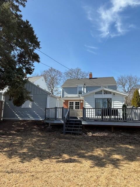 rear view of house featuring a wooden deck and a chimney