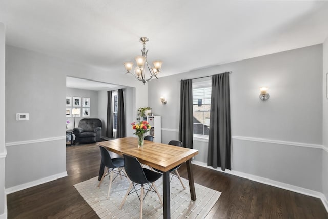 dining room featuring a chandelier, baseboards, and wood finished floors