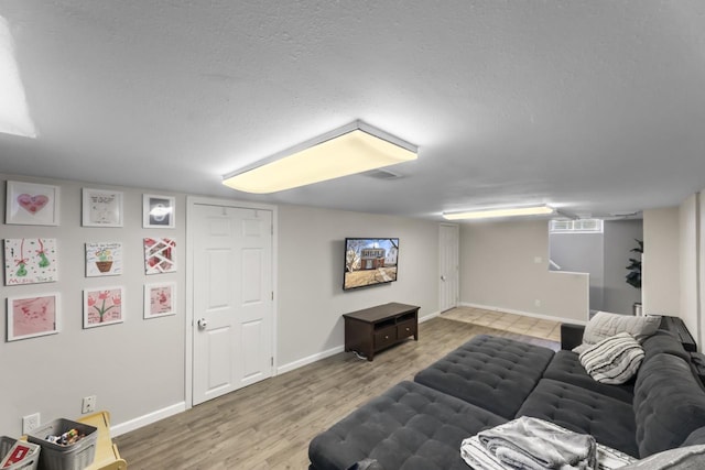 living area featuring visible vents, baseboards, a textured ceiling, and wood finished floors