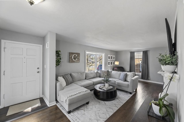 living room featuring dark wood finished floors, baseboards, and a wealth of natural light