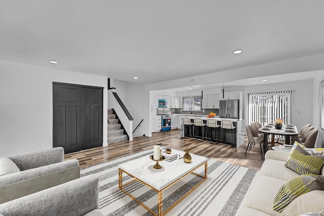 living room with a healthy amount of sunlight, stairs, wood finished floors, and recessed lighting