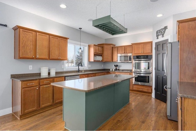 kitchen featuring stainless steel appliances, dark wood-style flooring, a sink, and brown cabinets