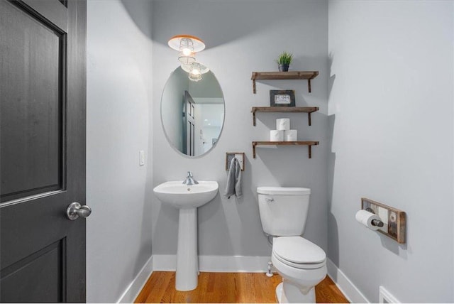 bathroom featuring toilet, baseboards, and wood finished floors