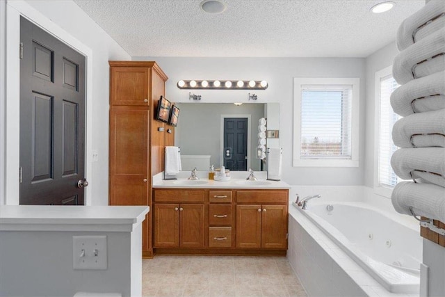 bathroom featuring a textured ceiling, double vanity, a jetted tub, and a sink