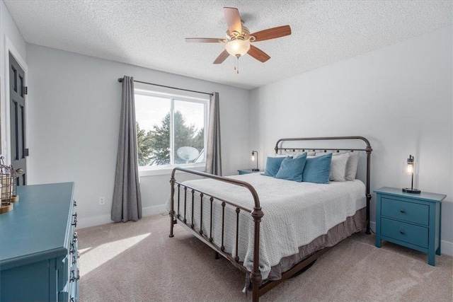 bedroom featuring a ceiling fan, baseboards, a textured ceiling, and light colored carpet