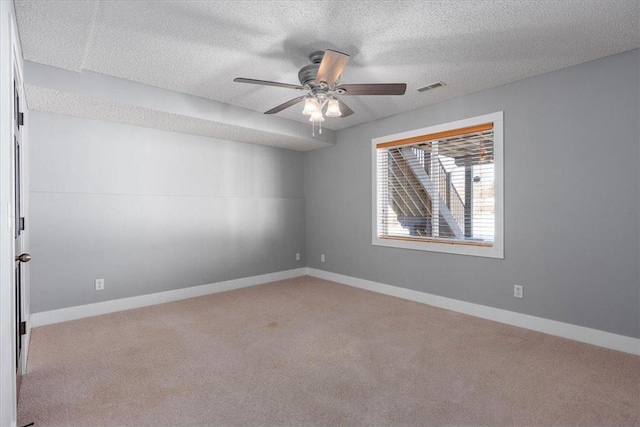 empty room featuring baseboards, visible vents, a ceiling fan, carpet, and a textured ceiling