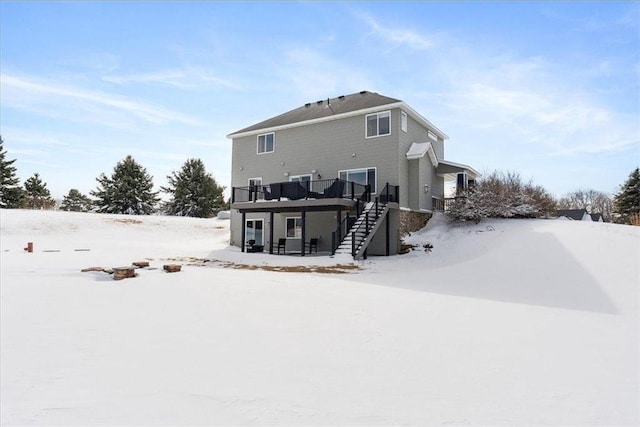 snow covered rear of property featuring a wooden deck and stairs