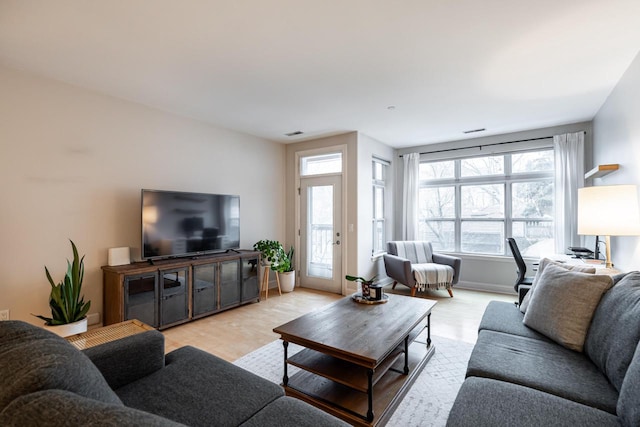 living room with baseboards, visible vents, and light wood finished floors