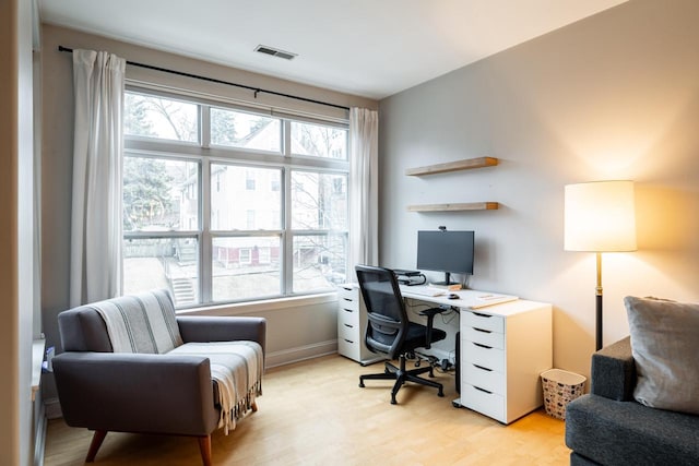 office space featuring baseboards, visible vents, and light wood finished floors