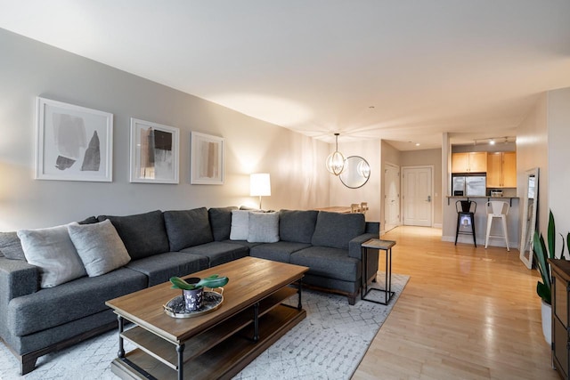 living area featuring baseboards, a notable chandelier, and light wood finished floors