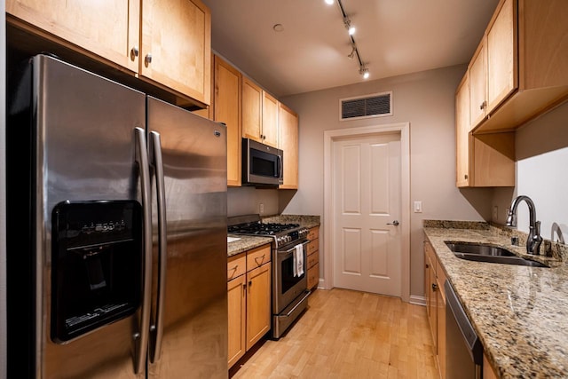 kitchen with light wood finished floors, visible vents, light stone countertops, stainless steel appliances, and a sink