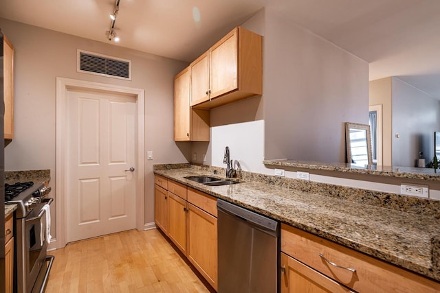 kitchen featuring light stone counters, stainless steel appliances, a sink, visible vents, and light wood finished floors