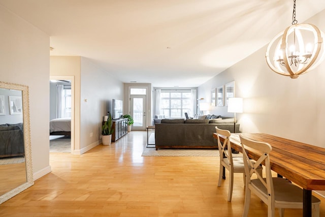 dining room featuring light wood-type flooring, baseboards, and a notable chandelier