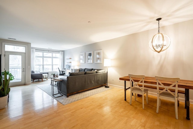 living area with light wood-style floors, a chandelier, visible vents, and baseboards