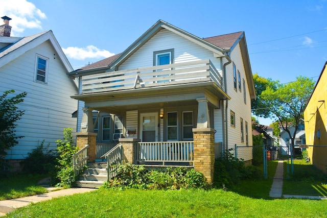 view of front facade featuring a porch, a gate, fence, and a balcony