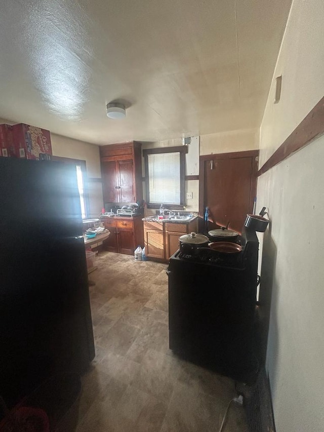 kitchen with brown cabinets, a sink, and freestanding refrigerator