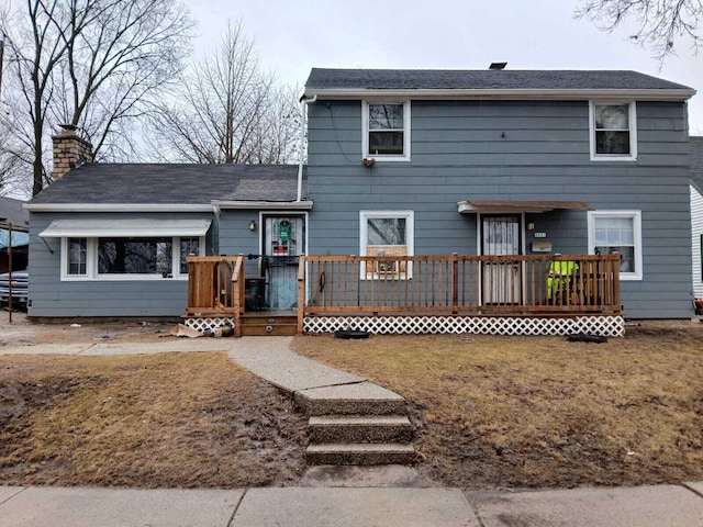 view of front of house with a chimney, a deck, and a front lawn