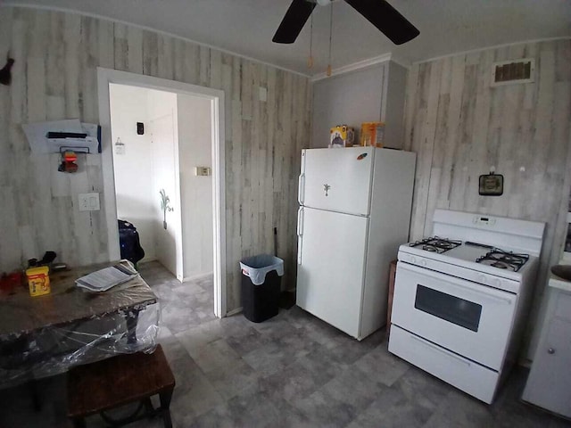 kitchen featuring white appliances, wooden walls, visible vents, and a ceiling fan