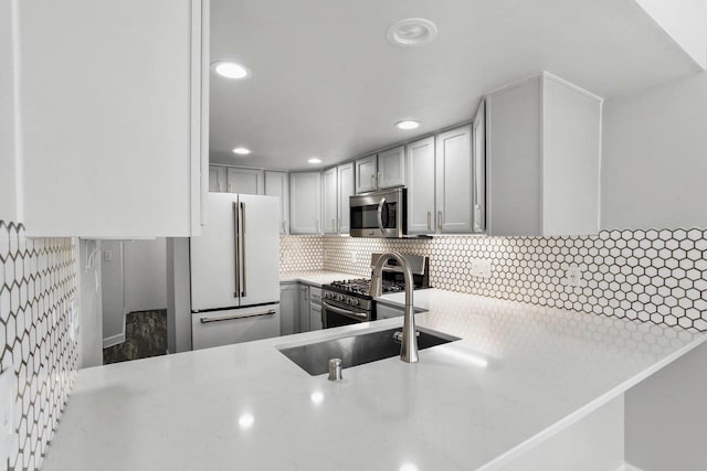 kitchen featuring stainless steel appliances, recessed lighting, gray cabinets, decorative backsplash, and light stone countertops