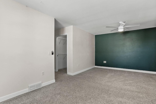 empty room featuring carpet floors, ceiling fan, visible vents, and baseboards