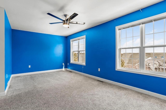 carpeted spare room featuring ceiling fan and baseboards