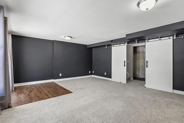 finished basement featuring carpet flooring, visible vents, and a barn door