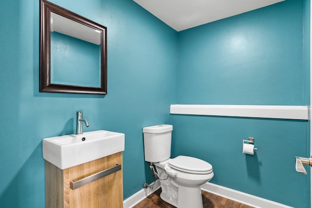 bathroom with toilet, baseboards, wood finished floors, and vanity