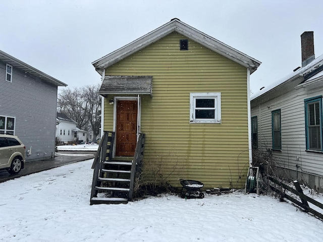 snow covered rear of property featuring entry steps