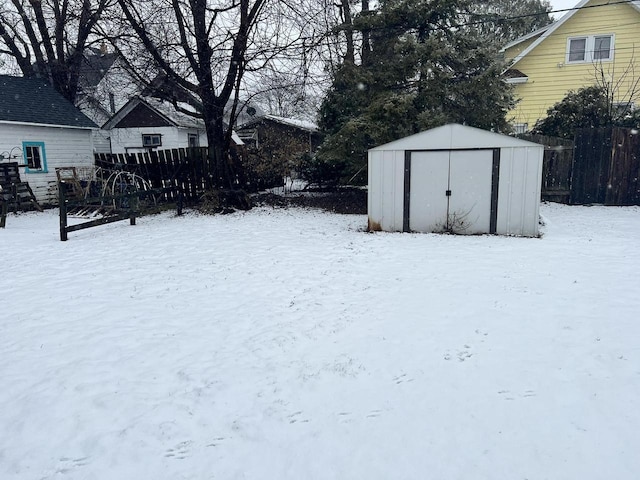 yard covered in snow featuring a shed, fence, and an outbuilding