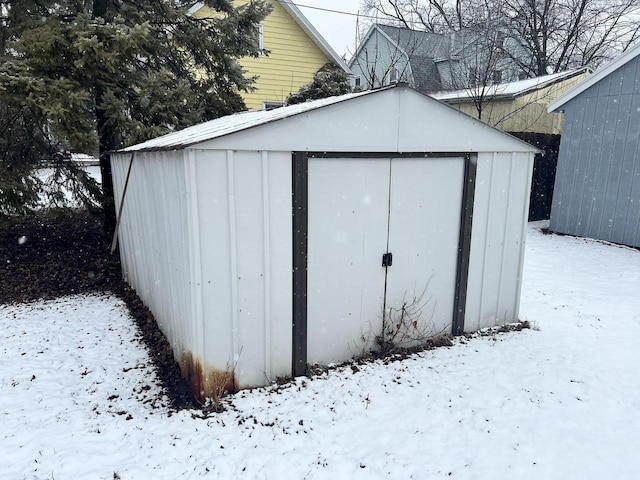 snow covered structure featuring an outdoor structure and a storage shed